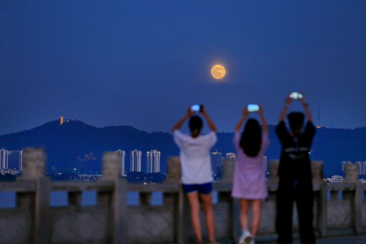 7月13日，在广东省鹤山市，市民在西江河畔观赏“超级月亮”。新华社发（黄继明 摄）