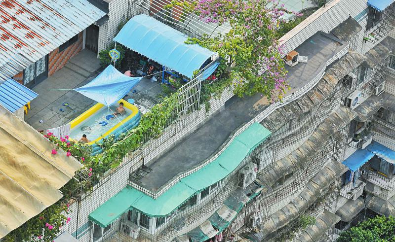 7月25日，成都市海角石西街一住户在屋顶装配的绵薄充气浴盆成了孩子们的避暑乐土。