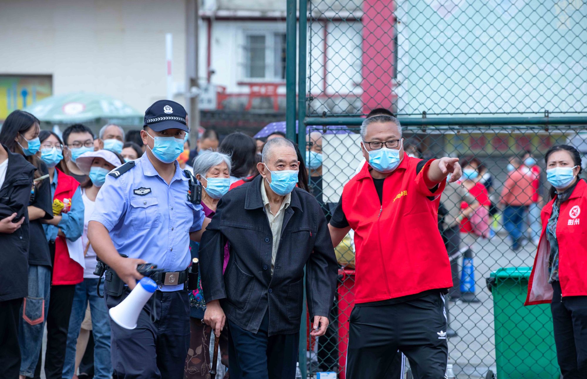 彭州，公安干警和志愿者帮助引导居民检测核酸  摄影：张鸿
