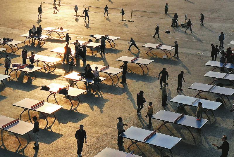 夕阳下，市民们在省体育馆的广场上打乒乓球。