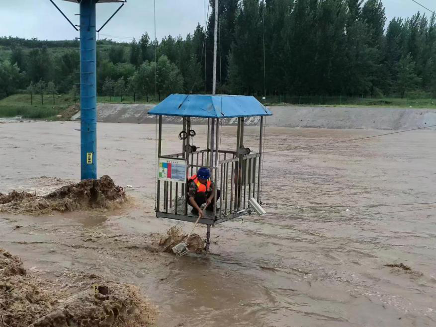 7月30日，水文工作人员冒雨在湍急的河流中完成测流作业 河北省水文勘测研究中心供图