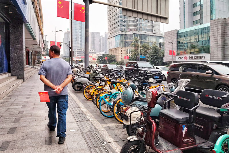 路人-国庆临近，一路人走过挂满国旗的街道