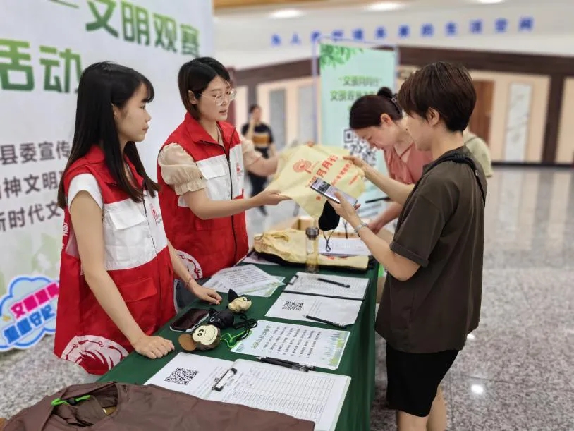 ↑ 在成都大邑县“生活垃圾分类达人说”演讲比赛赛场外，志愿者为前来观赛的市民发出文明观赛倡议，并发放小礼物。