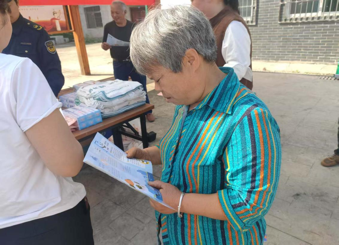 ▲社区居民认真阅读节水资料（图源：东部新区河长办）