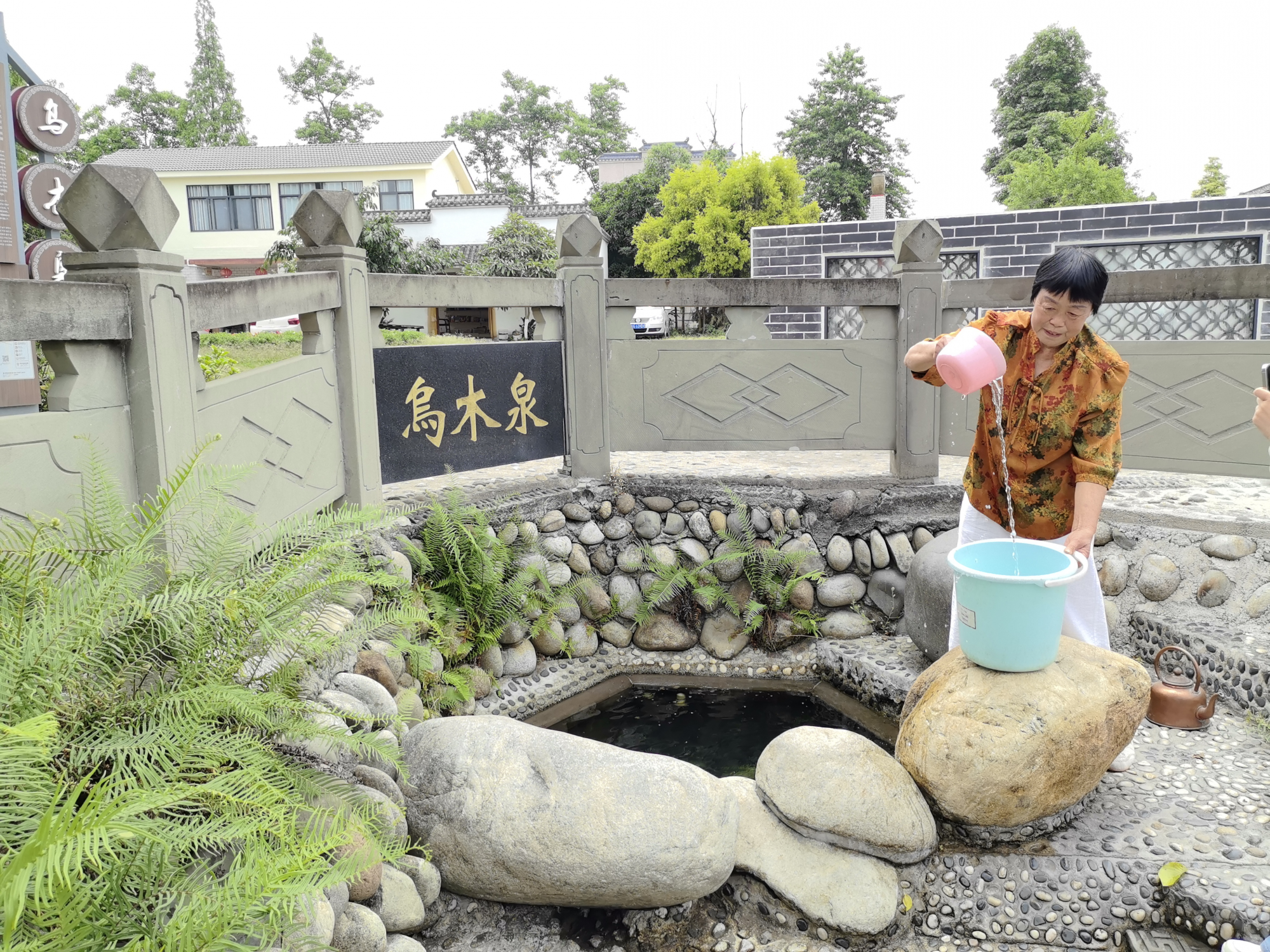 ▲村民宁顺珍在乌木泉打泉水（摄影：吴渝）