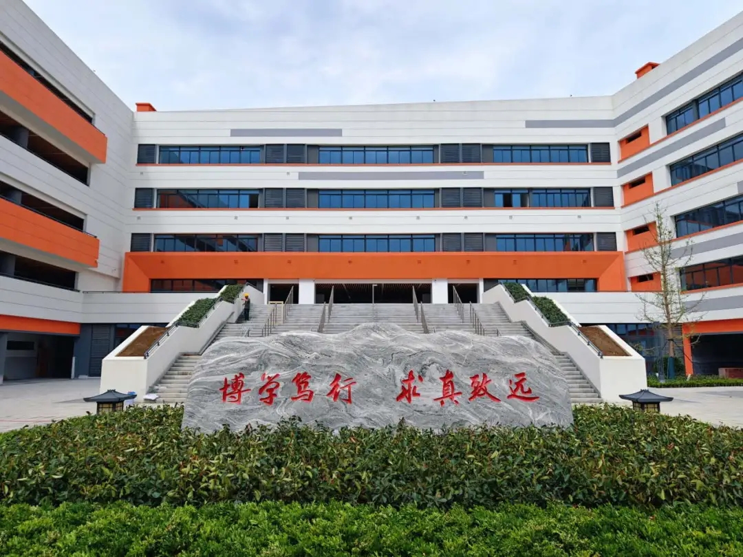 校园建筑以纯净的白色与温暖的橙色为主色调，校园基础设施完备，功能分区科学合理，教学区、运动区、办公区以及公共活动区规划有序，为师生提供了全方位的学习与生活空间。